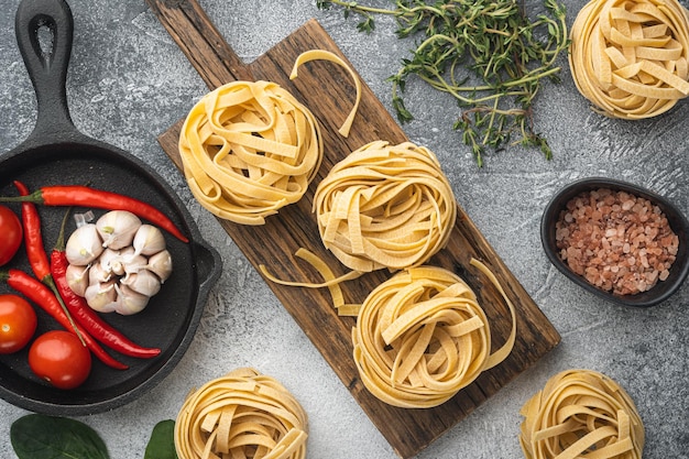 Tagliatelle di pasta con ingredienti su sfondo grigio pietra vista dall'alto piatto