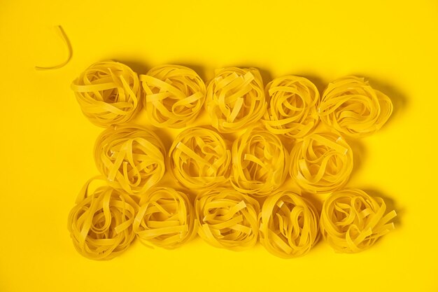 Tagliatelle di pasta italiane isolate su sfondo giallo