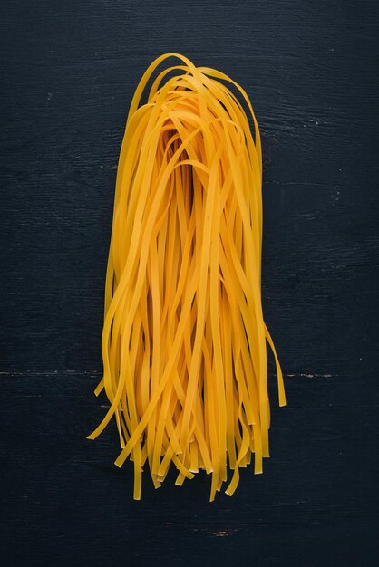 Tagliatelle di pasta secca fettuccine su fondo di legno Vista dall'alto Spazio di copia