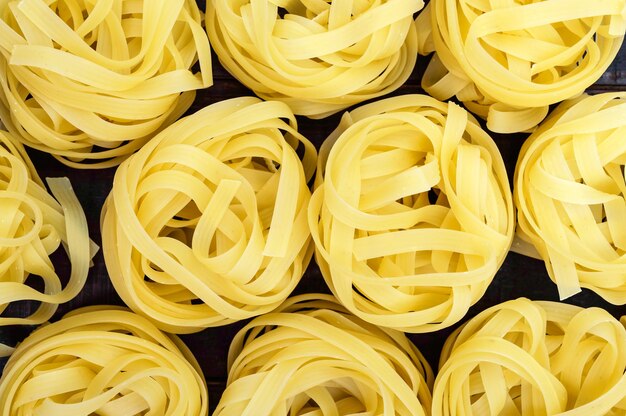 Tagliatelle di pasta sotto forma di nidi Sfondo alimentare La vista dall'alto Primo piano