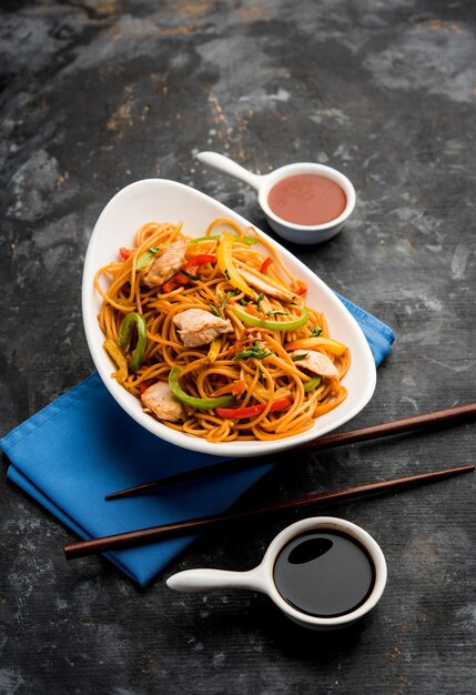 Tagliatelle di pollo Hakka o Schezwan servite in una ciotola con le bacchette