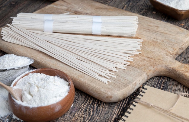 Tagliatelle di riso bianche e farina e altri ingredienti che cucinano le tagliatelle di riso su un primo piano della tavola di legno