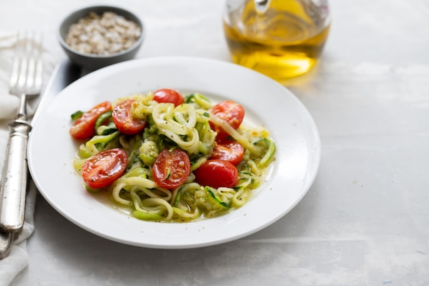 Tagliatelle di zucchine a spirale con pomodoro sul piatto bianco