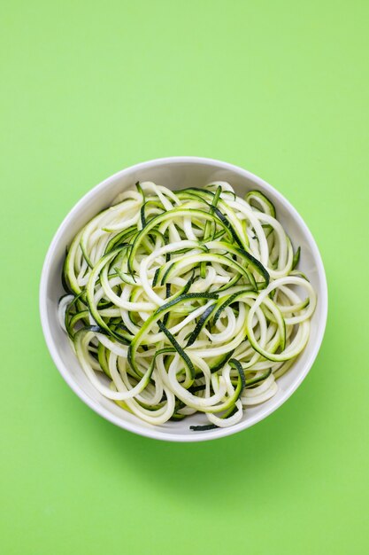 Tagliatelle di zucchine in ciotola su fondo verde