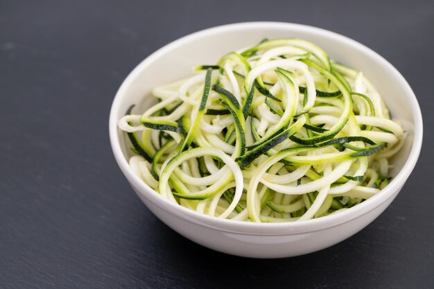 Tagliatelle di zucchine in ciotola su sfondo scuro