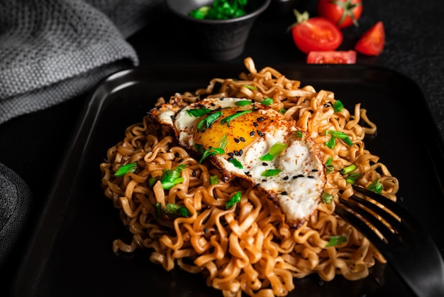 Tagliatelle fresche calde con fondo scuro dell'uovo fritto. Foto di alta qualità