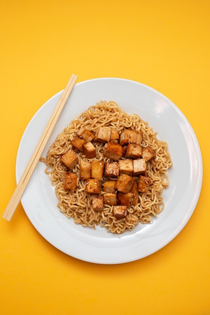 Tagliatelle fritte con tofu sul piatto bianco