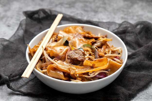 Tagliatelle fritte con verdure e manzo in una ciotola bianca