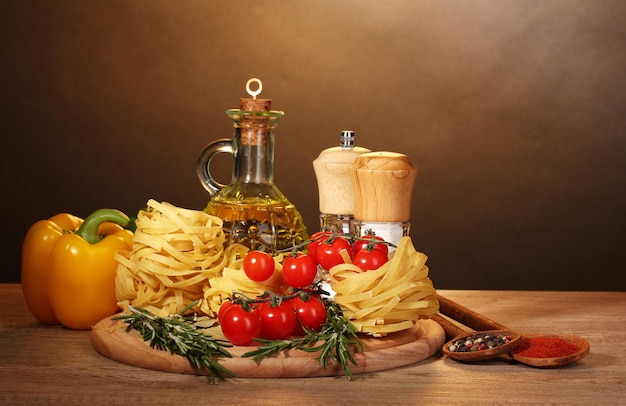 Tagliatelle in barattolo di olio spezie e verdure sulla tavola di legno su sfondo marrone