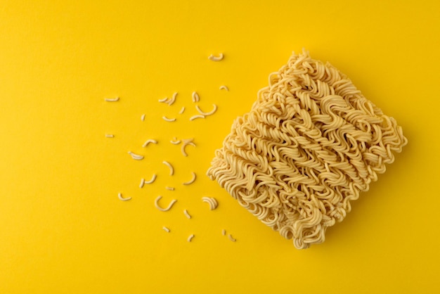 Tagliatelle istantanee asciutte su sfondo giallo.