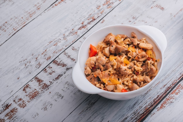 Tagliatelle istantanee con pollo e pepe con salsa piccante in una ciotola bianca