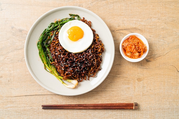 Tagliatelle istantanee con salsa nera piccante coreana essiccate fatte in casa con uovo fritto e kimchi