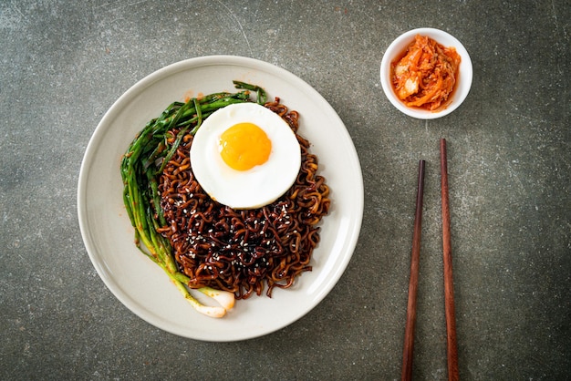 Tagliatelle istantanee con salsa nera piccante coreana essiccate fatte in casa con uovo fritto e kimchi