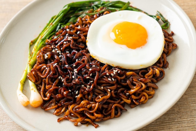 Tagliatelle istantanee con salsa nera piccante coreana essiccate fatte in casa con uovo fritto e kimchi