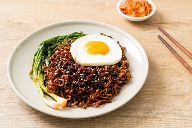 Tagliatelle istantanee con salsa nera piccante coreana essiccate fatte in casa con uovo fritto e kimchi