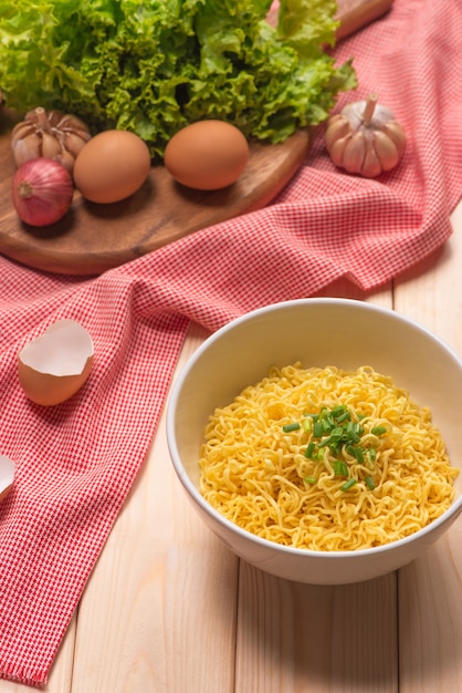 Tagliatelle istantanee in ciotola con verdure su fondo di legno