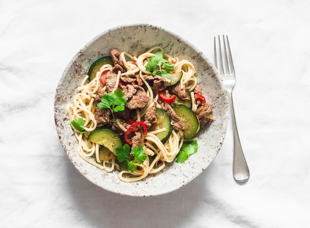 Tagliatelle piccanti con peperone di manzo e zucchine un delizioso pranzo su uno sfondo chiaro vista dall'alto