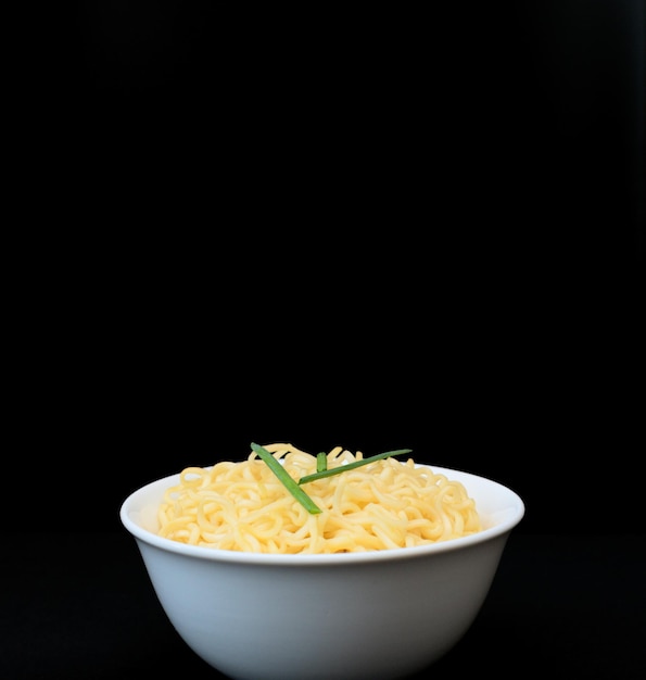 Tagliatelle ricci cinesi istantanee in una ciotola bianca su sfondo nero Fuoco selettivo Concetto di cibo asiatico Mangiare malsano