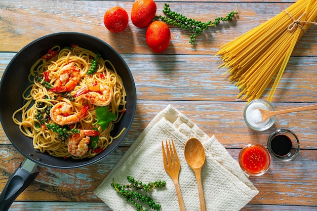 Tagliatelle saltate in padella con verdure e gamberi in padella di ferro nero Sfondo ardesia Vista dall'alto