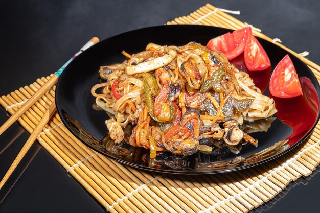 Tagliatelle Udon con carne di funghi e verdure Cosparse di semi di sesamo Arrosto di cibo asiatico su sfondo nero