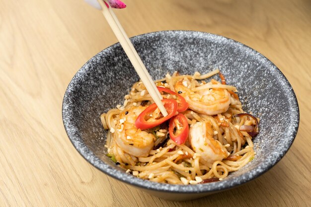 Tagliatelle Udon con gamberetti e verdure fritte in una ciotola vista dall'alto