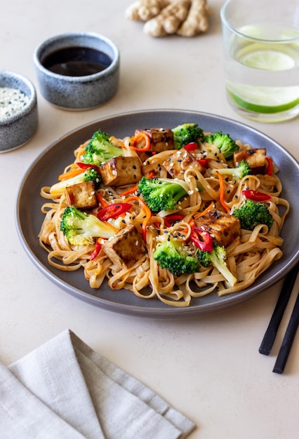 Tagliatelle Udon con tofu broccoli carote pepe e sesamo Alimentazione sana Cibo vegetariano Cibo asiatico