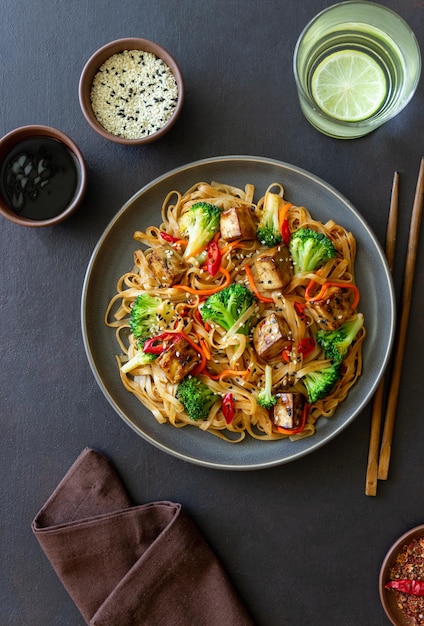 Tagliatelle Udon con tofu broccoli carote pepe e sesamo Alimentazione sana Cibo vegetariano Cibo asiatico