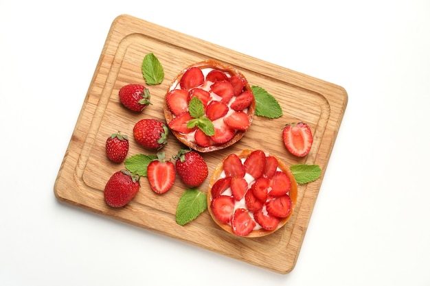 Tagliere con crostate di fragole su sfondo bianco.