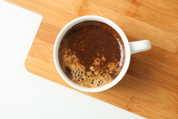 Tagliere con la tazza di caffè fresco su fondo bianco