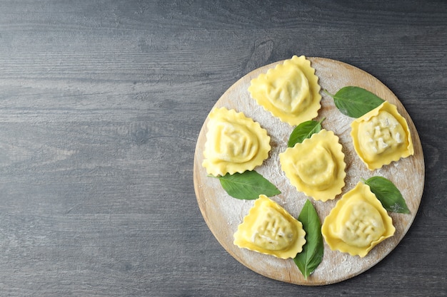 Tagliere con ravioli crudi su fondo di legno scuro