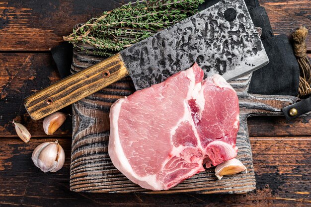 Tagliere da macellaio con bistecca di carne di maiale cruda Tbone sfondo di legno Vista dall'alto