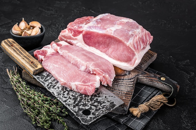 Tagliere da macellaio con filetto di lombo di maiale crudo affettato pronto per cucinare bistecche Sfondo nero Vista dall'alto