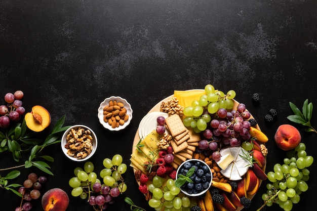 Tagliere di formaggi autunnali con frutta fresca e frutti di bosco serviti con vista dall'alto di vino bianco