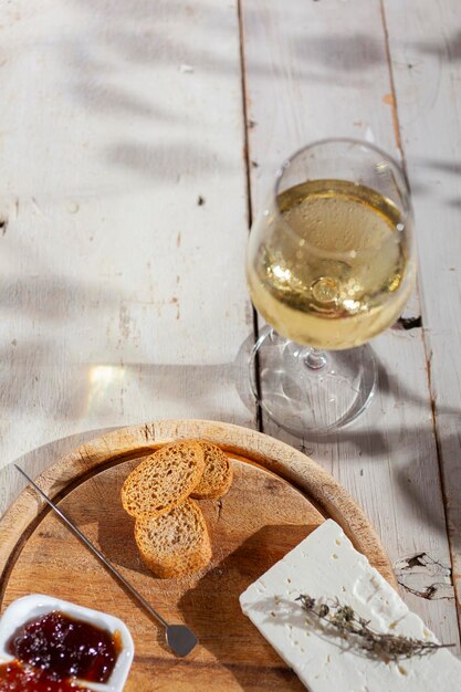 Tagliere di formaggi servito con marmellata e vino bianco fresco