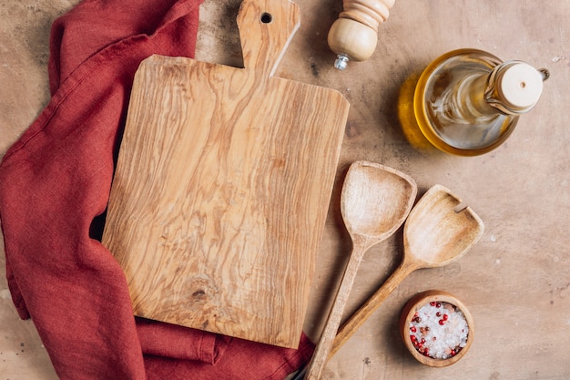 Tagliere di legno sopra l'asciugamano con gli utensili sul tavolo da cucina ructic.