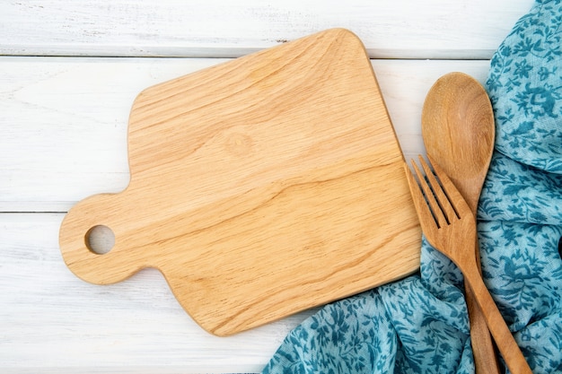 tagliere e tovaglia con la forchetta e il cucchiaio di legno sul tavolo bianco