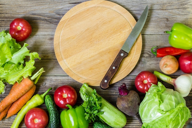 Tagliere e verdure del cerchio su fondo di legno. Mangiare sano