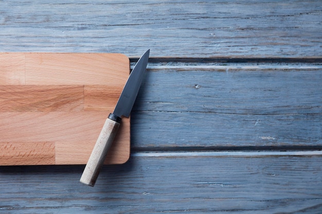 Tagliere in legno e coltello su uno sfondo di tavolato in legno rustico