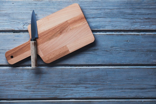 Tagliere in legno e coltello su uno sfondo di tavolato in legno rustico