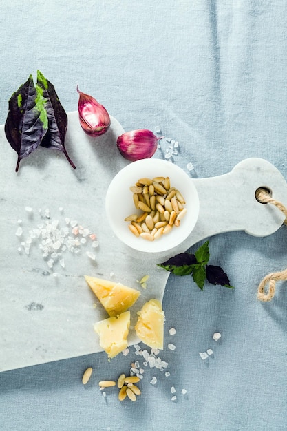 Tagliere in marmo e spezie su una tovaglia blu di lino olio d'oliva pinoli e basilico copia spazio