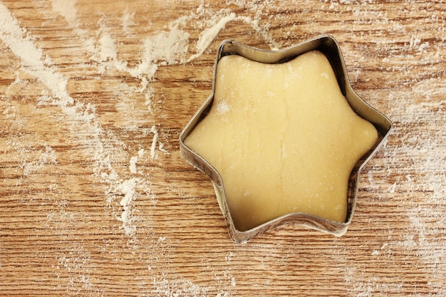 Taglierina per la pasta ai biscotti crudi su un primo piano di tavolo in legno