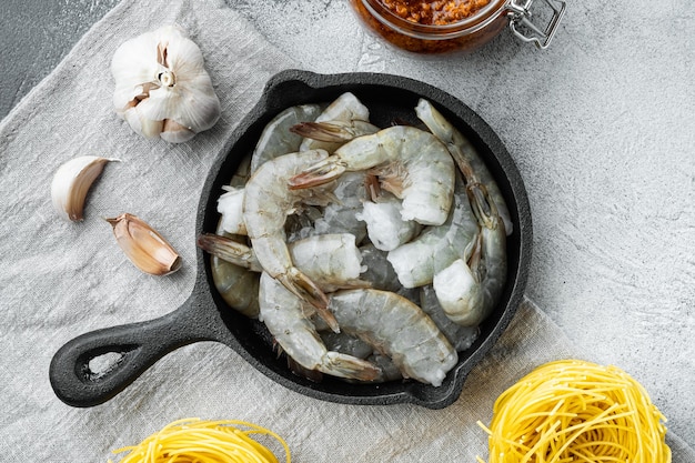 Taglierini di pasta con salsa al pesto e set di ingredienti di gamberetti, sul tavolo di pietra grigia, vista dall'alto laici piatta