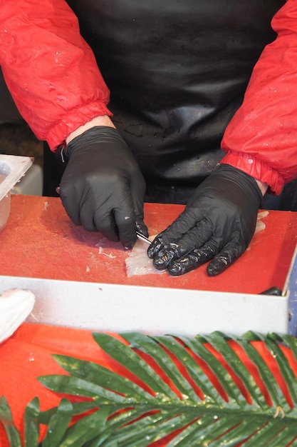 Taglio a mano del salmone sulla tavola rossa in un gesto di primo piano