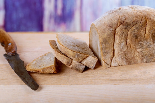 Taglio del pane del grano saraceno sul bordo di legno in cucina