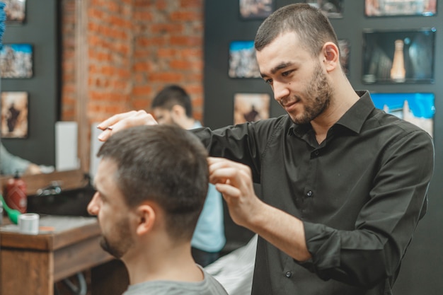 Taglio di capelli dal parrucchiere. Il barbiere taglia i capelli sulla testa del cliente