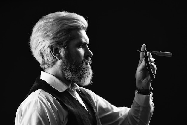 Taglio di capelli uomo nel negozio di barbiere baffi e rifiniture della barba pronto a tagliare i suoi clienti barbiere vintage maestro bell'uomo barbuto con barba lunga Barbiere professionista pronto a fare un taglio di capelli alla moda