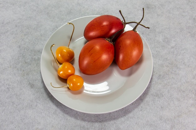 tamarillo o pomodoro albero su tavola di legno accanto a uvilla o aguaymanto physalis