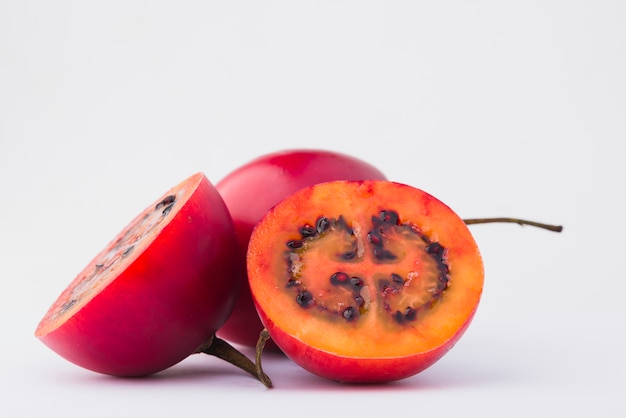 Tamarillo rosso con una fetta su sfondo bianco