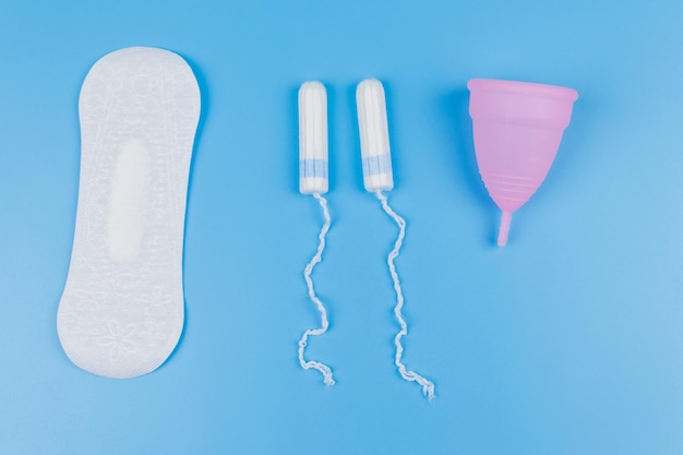 Tamponi igienici e coppetta mestruale su sfondo blu Vista dall'alto Concetto di giorni critici mestruazioni igiene femminile