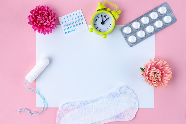 Tamponi per mestruazioni, sveglia, calendario da donna, cuscinetti femminili, pillole antidolorifiche per giorni critici e fiori. Cura dell'igiene nei giorni critici.